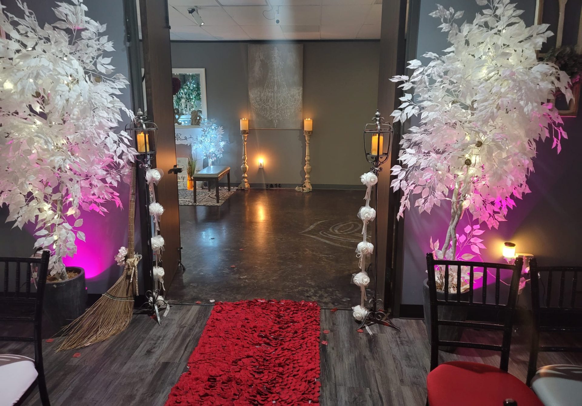Candlelit aisle inside The Chapel framed by white flowering trees and warm uplighting.