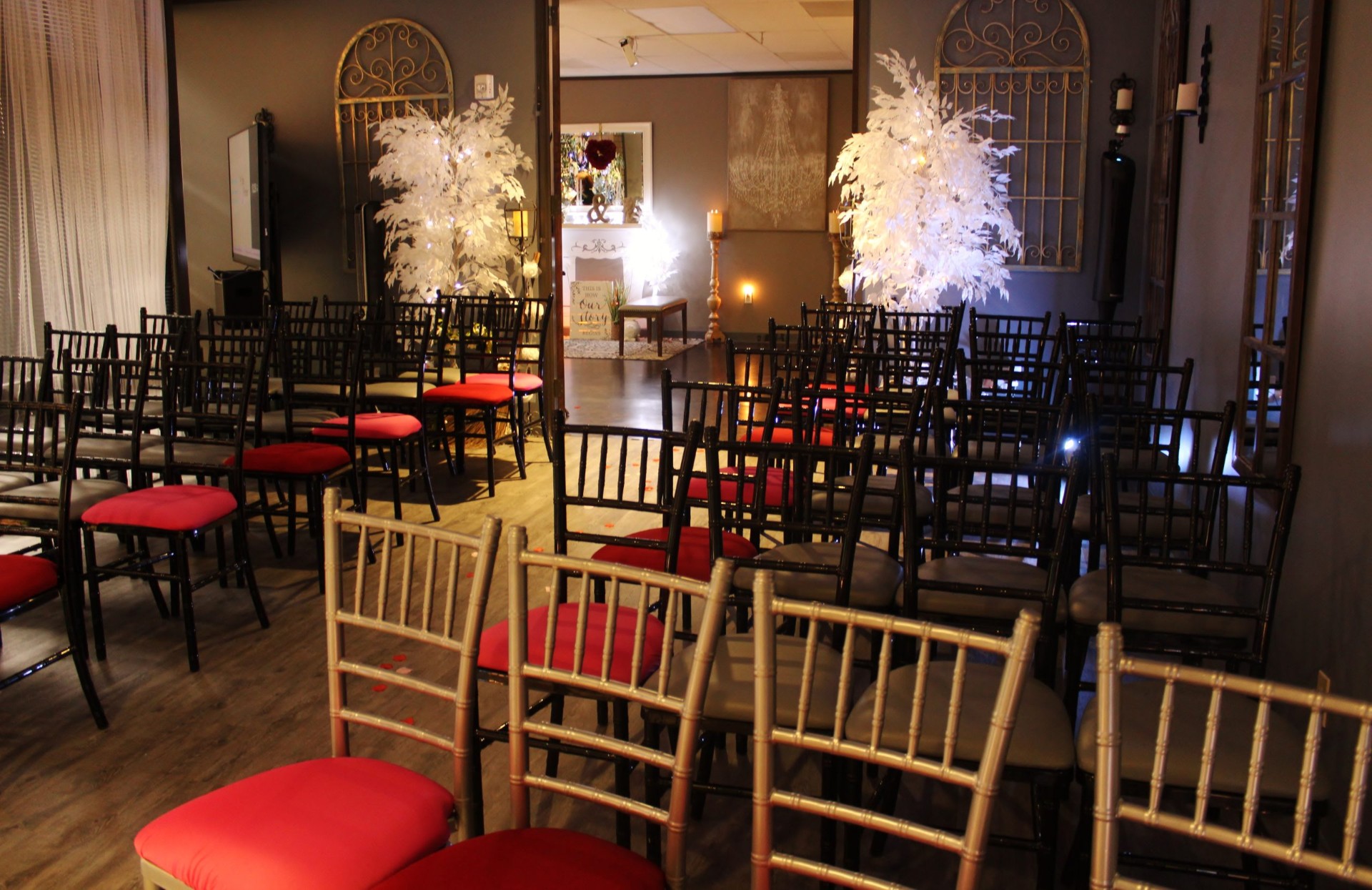 Warmly lit Chapel interior with arranged seating, floral trees, and candle details.